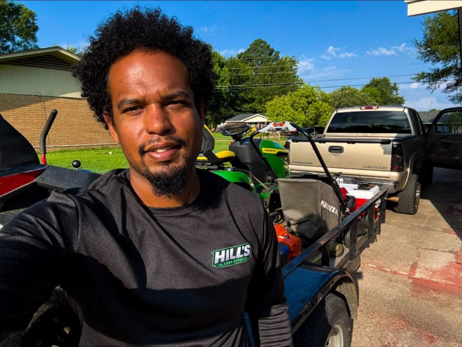 A Hill's Lawn Service crew member on the job beside the truck and equipment